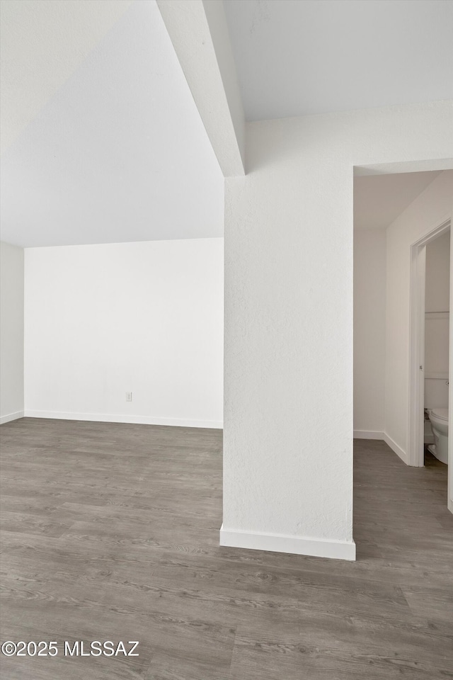 bonus room with dark wood finished floors and baseboards