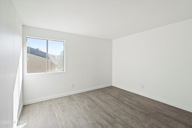 empty room featuring wood finished floors and baseboards