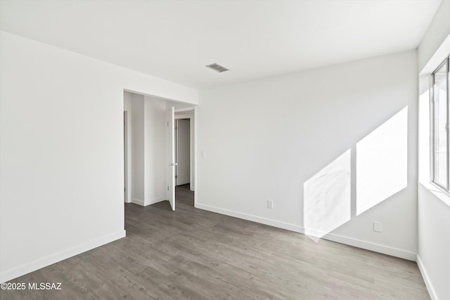 unfurnished room with wood finished floors, visible vents, and baseboards