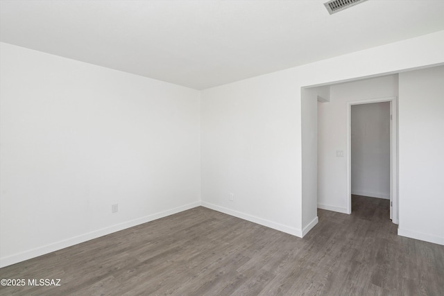 unfurnished room with visible vents, baseboards, and dark wood-style flooring