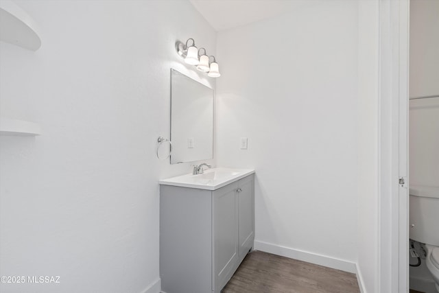 bathroom featuring baseboards, vanity, toilet, and wood finished floors