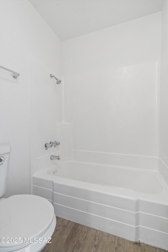 full bath featuring washtub / shower combination, wood finished floors, and toilet