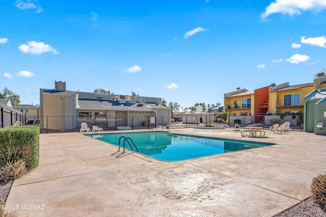 community pool featuring a patio area, a residential view, and fence