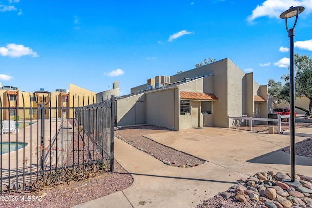 exterior space featuring a tile roof, a residential view, a gate, fence, and stucco siding