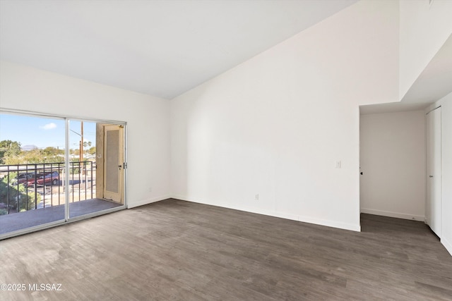 unfurnished room featuring high vaulted ceiling, dark wood finished floors, and baseboards