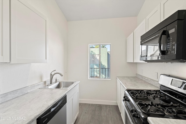 kitchen with light countertops, appliances with stainless steel finishes, white cabinetry, a sink, and baseboards