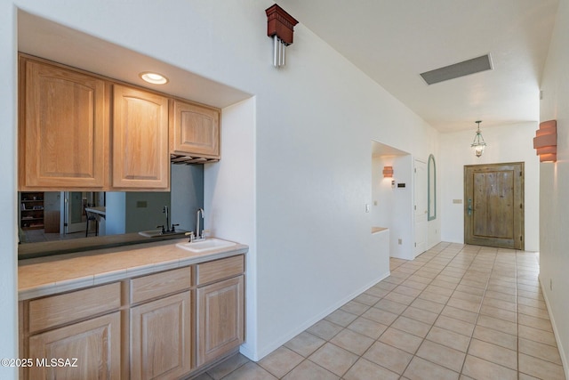 kitchen with light countertops, a sink, decorative light fixtures, and light tile patterned flooring