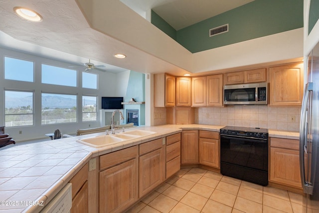 kitchen featuring tile counters, visible vents, appliances with stainless steel finishes, open floor plan, and a sink