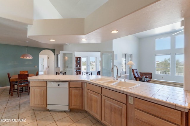 kitchen with a healthy amount of sunlight, white dishwasher, tile countertops, and a sink