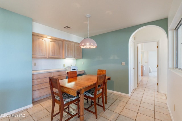 dining space featuring arched walkways, light tile patterned floors, visible vents, and baseboards