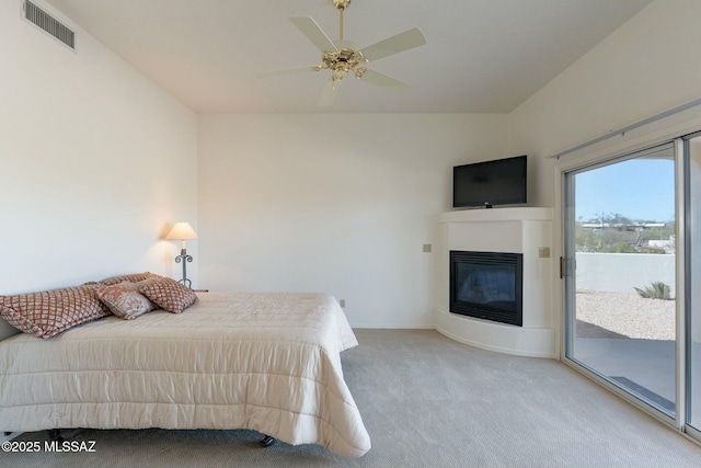 bedroom featuring visible vents, a glass covered fireplace, light carpet, ceiling fan, and access to outside