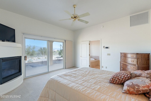 bedroom with visible vents, connected bathroom, a glass covered fireplace, light colored carpet, and access to exterior