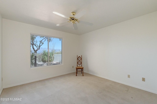 spare room with light carpet, baseboards, and a ceiling fan