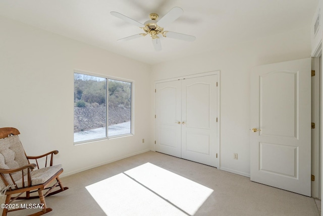 interior space with a ceiling fan, a closet, light colored carpet, and baseboards