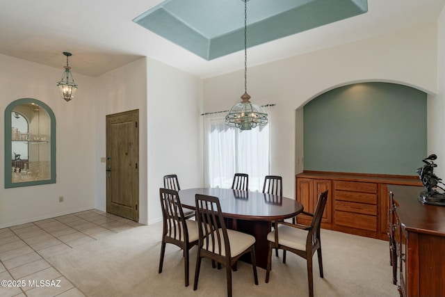 dining room featuring a raised ceiling and light tile patterned flooring