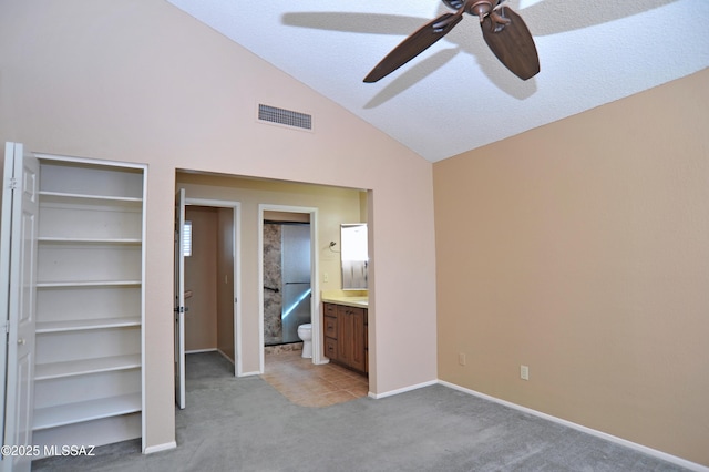 unfurnished bedroom with baseboards, visible vents, a ceiling fan, light colored carpet, and vaulted ceiling