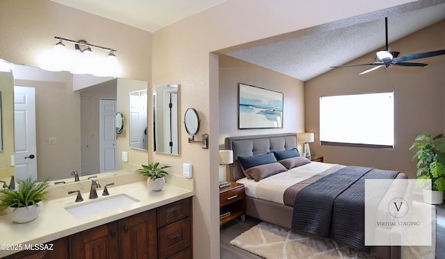 bedroom with a textured ceiling, vaulted ceiling, and a sink