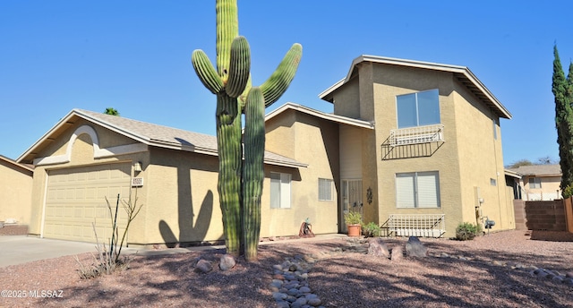 view of front of property with driveway, an attached garage, fence, and stucco siding