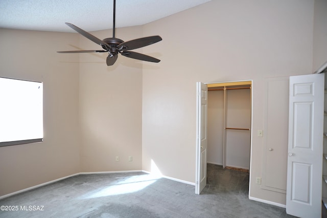 unfurnished bedroom featuring a walk in closet, a closet, dark carpet, a textured ceiling, and baseboards