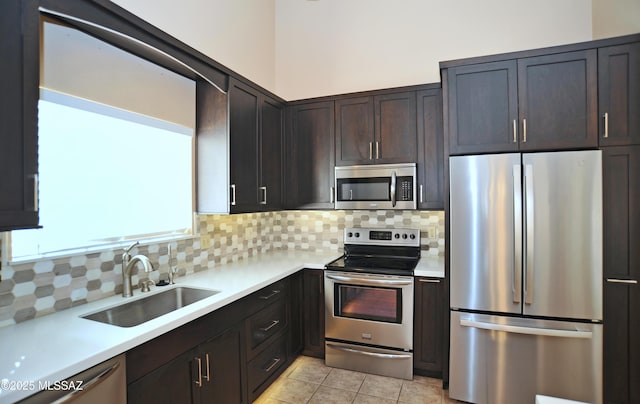 kitchen with light tile patterned floors, a sink, light countertops, appliances with stainless steel finishes, and backsplash