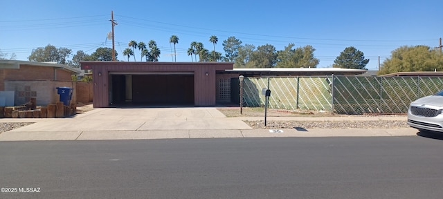 view of front facade with driveway, an outdoor structure, and fence