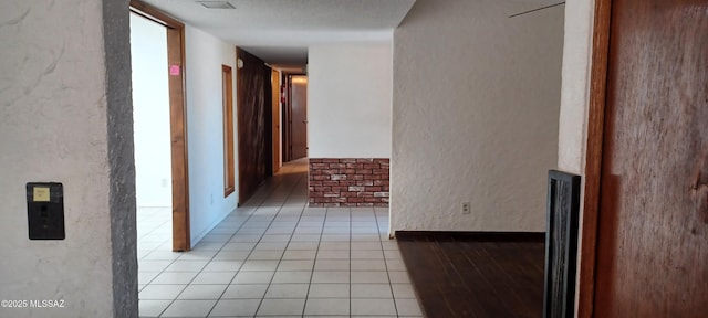 hall with light tile patterned floors and a textured wall