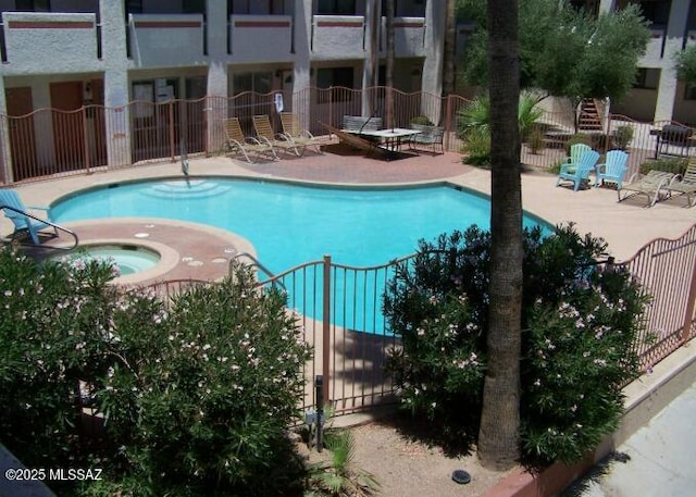 pool with a patio area, fence, and a hot tub