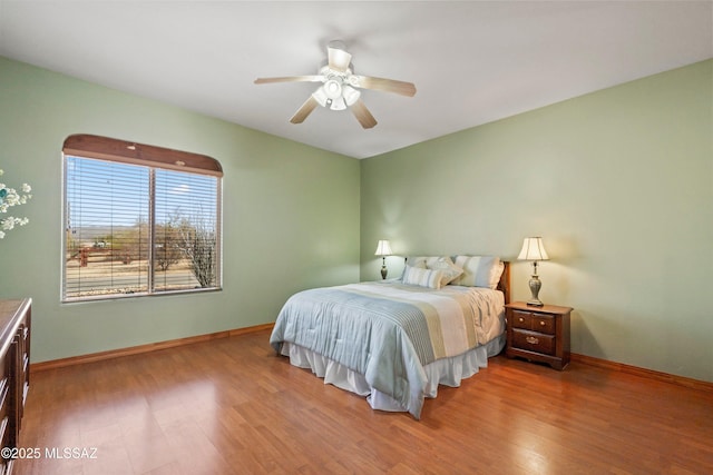 bedroom with ceiling fan, baseboards, and wood finished floors