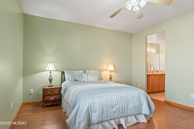 bedroom with baseboards, ensuite bathroom, a ceiling fan, and light wood-style floors