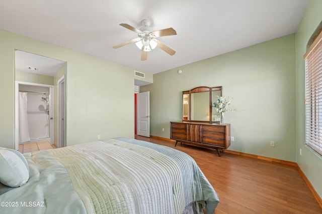 bedroom with a ceiling fan, visible vents, baseboards, and wood finished floors