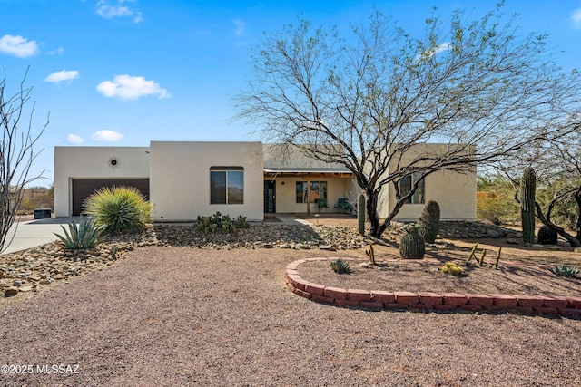 pueblo-style home with a garage, concrete driveway, and stucco siding