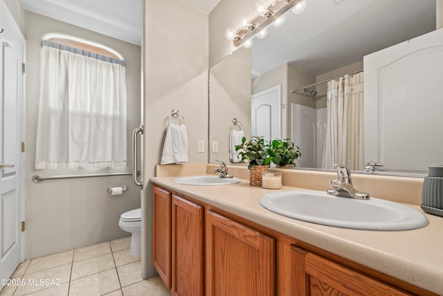 bathroom featuring double vanity, a sink, toilet, and tile patterned floors