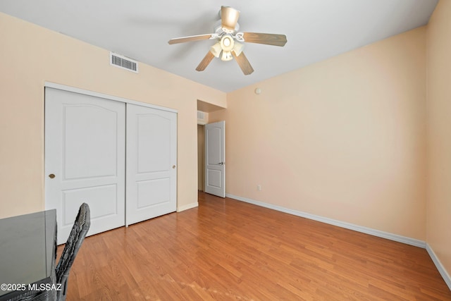 unfurnished bedroom featuring a closet, visible vents, light wood-style flooring, a ceiling fan, and baseboards