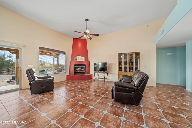 living area featuring ceiling fan, a fireplace, visible vents, and tile patterned floors