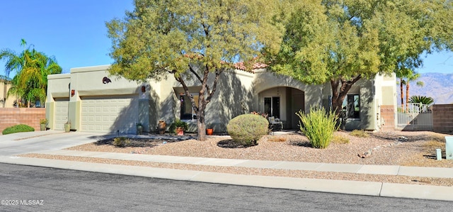 view of front of home featuring driveway, an attached garage, fence, and stucco siding