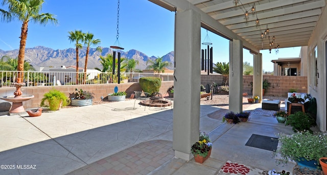 view of patio / terrace with an outdoor fire pit, fence, and a mountain view