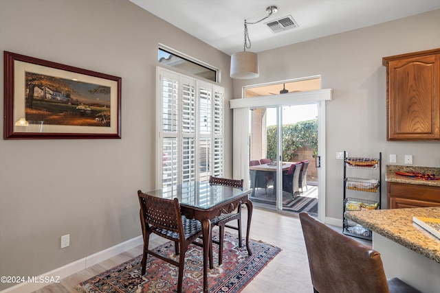 dining room featuring light wood-type flooring, visible vents, and baseboards