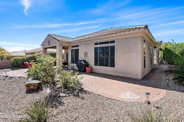 rear view of property featuring a patio area, fence, a tiled roof, and stucco siding