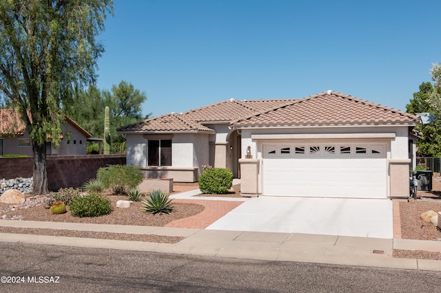 view of front facade featuring an attached garage, fence, a tile roof, concrete driveway, and stucco siding