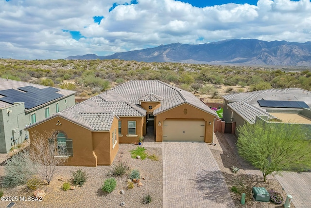 view of front of house featuring a mountain view, a garage, a tiled roof, decorative driveway, and stucco siding