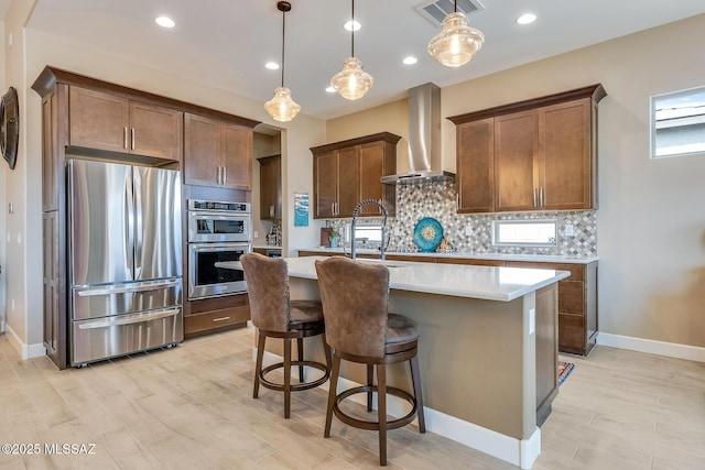 kitchen with visible vents, decorative backsplash, appliances with stainless steel finishes, light countertops, and wall chimney range hood