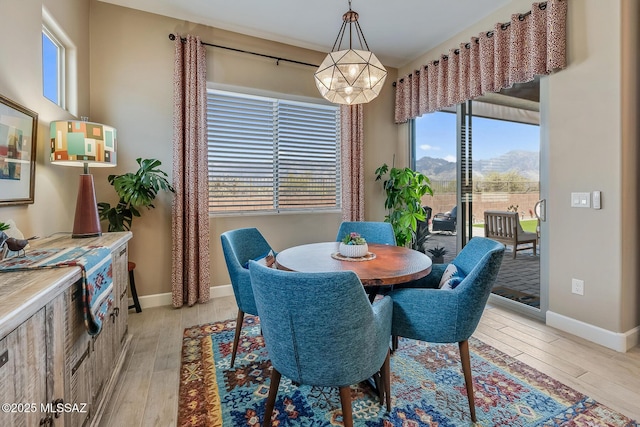 dining space with light wood-style floors, a mountain view, and baseboards