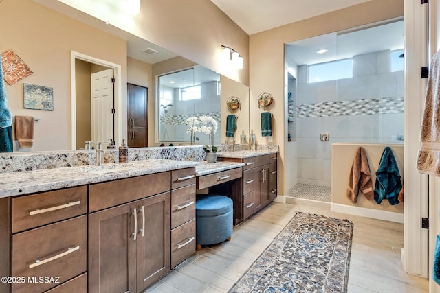 bathroom with wood finished floors, visible vents, vanity, and a walk in shower