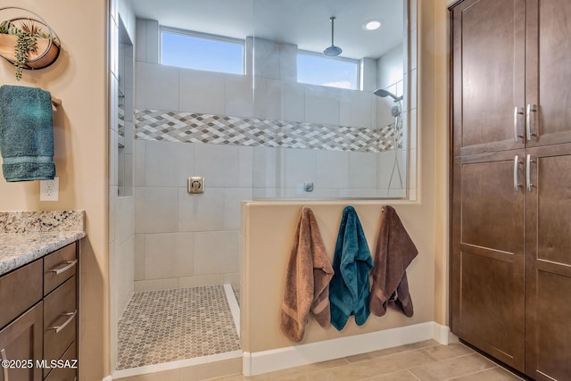 full bathroom featuring tiled shower, vanity, and baseboards