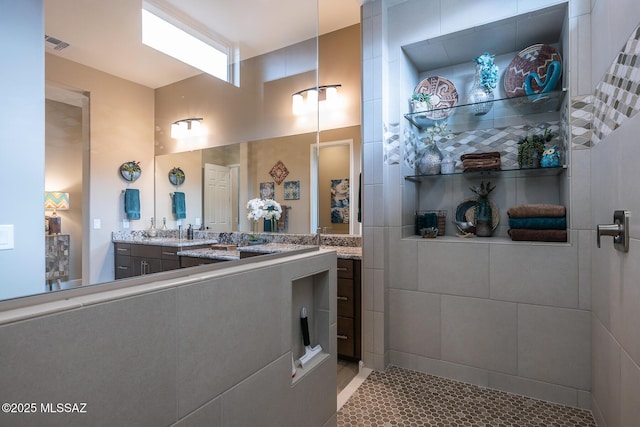 bathroom featuring visible vents, a walk in shower, and vanity