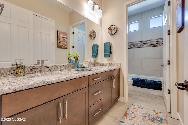 bathroom with double vanity, toilet, tub / shower combination, and a sink