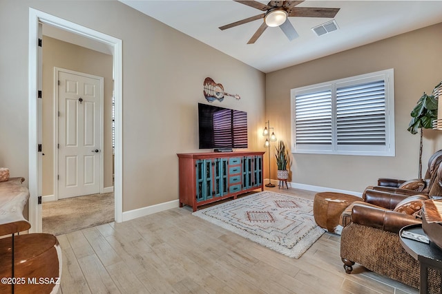 living room featuring baseboards, wood finished floors, visible vents, and a ceiling fan