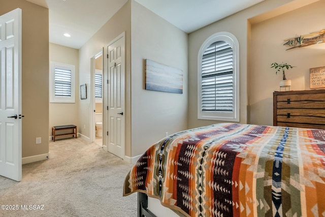 bedroom with carpet floors, connected bathroom, and baseboards