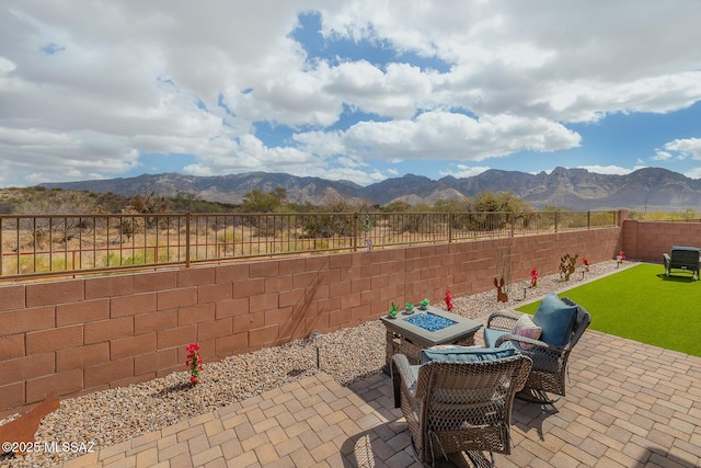 view of patio / terrace with a fire pit, a fenced backyard, and a mountain view