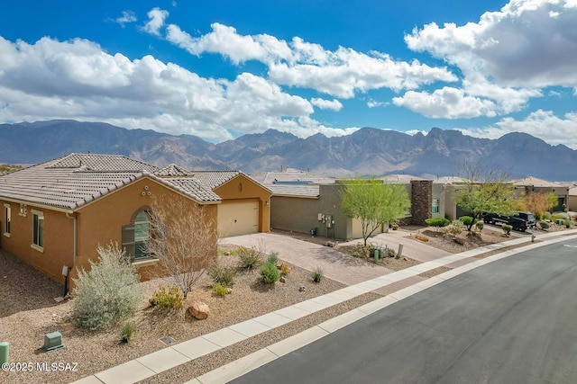 view of front of home with driveway, a tile roof, a mountain view, and stucco siding